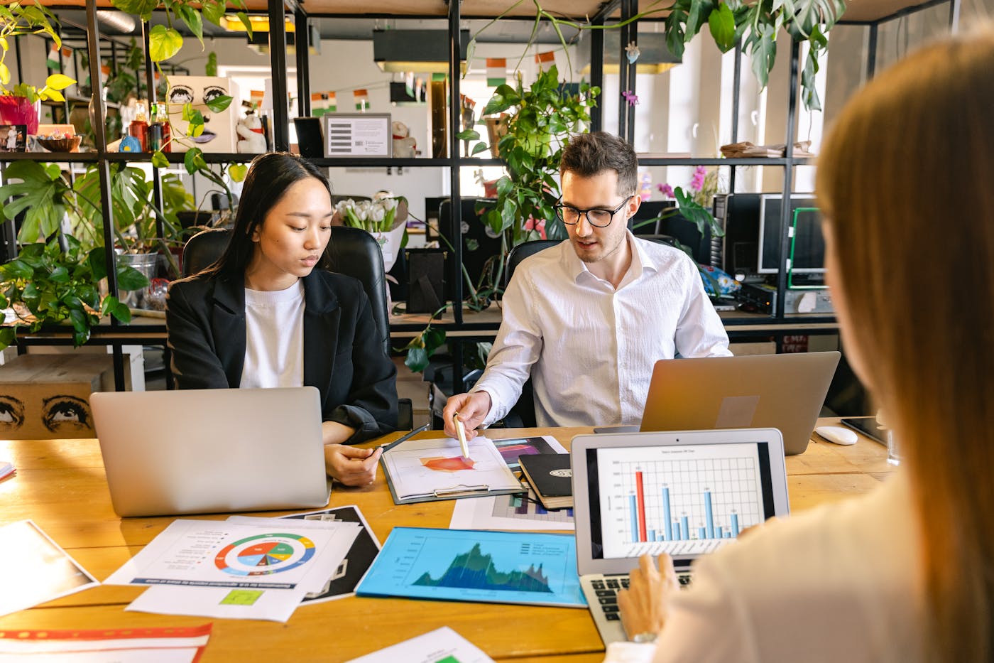 A leadership team reviewing charts, laptops, and planning materials in a modern office.